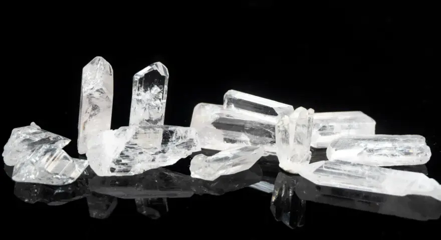 Raw danburite crystals on a black reflective surface, hinting at their powerful danburite metaphysical properties for spiritual growth and angelic connection.