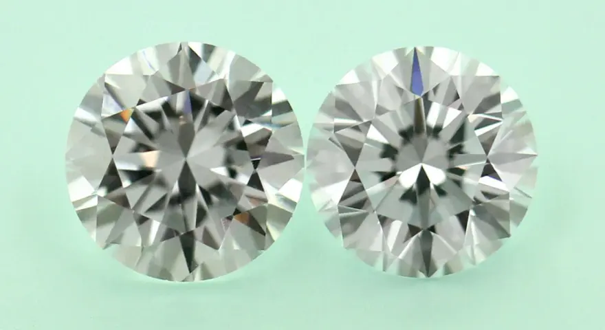 Two round brilliant cut diamonds, one a diamond simulant and the other lab grown, are shown side-by-side on a pale green background.