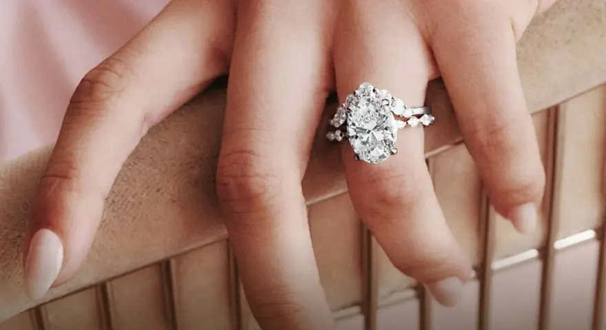 A hand displays a stunning oval diamond engagement ring, sparking the question: are brilliant earth diamonds real?