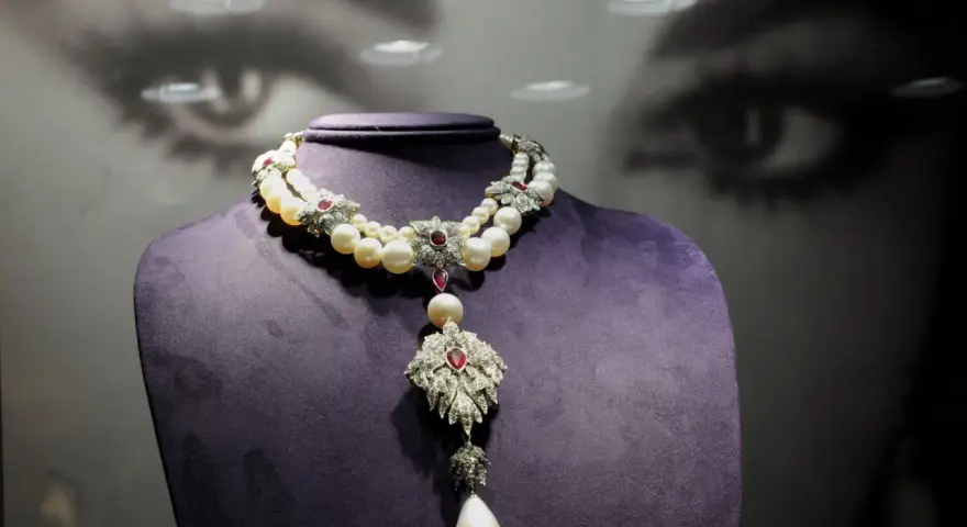 A stunning pearl and ruby necklace, reminiscent of "La Peregrina," drapes elegantly over a purple bust.