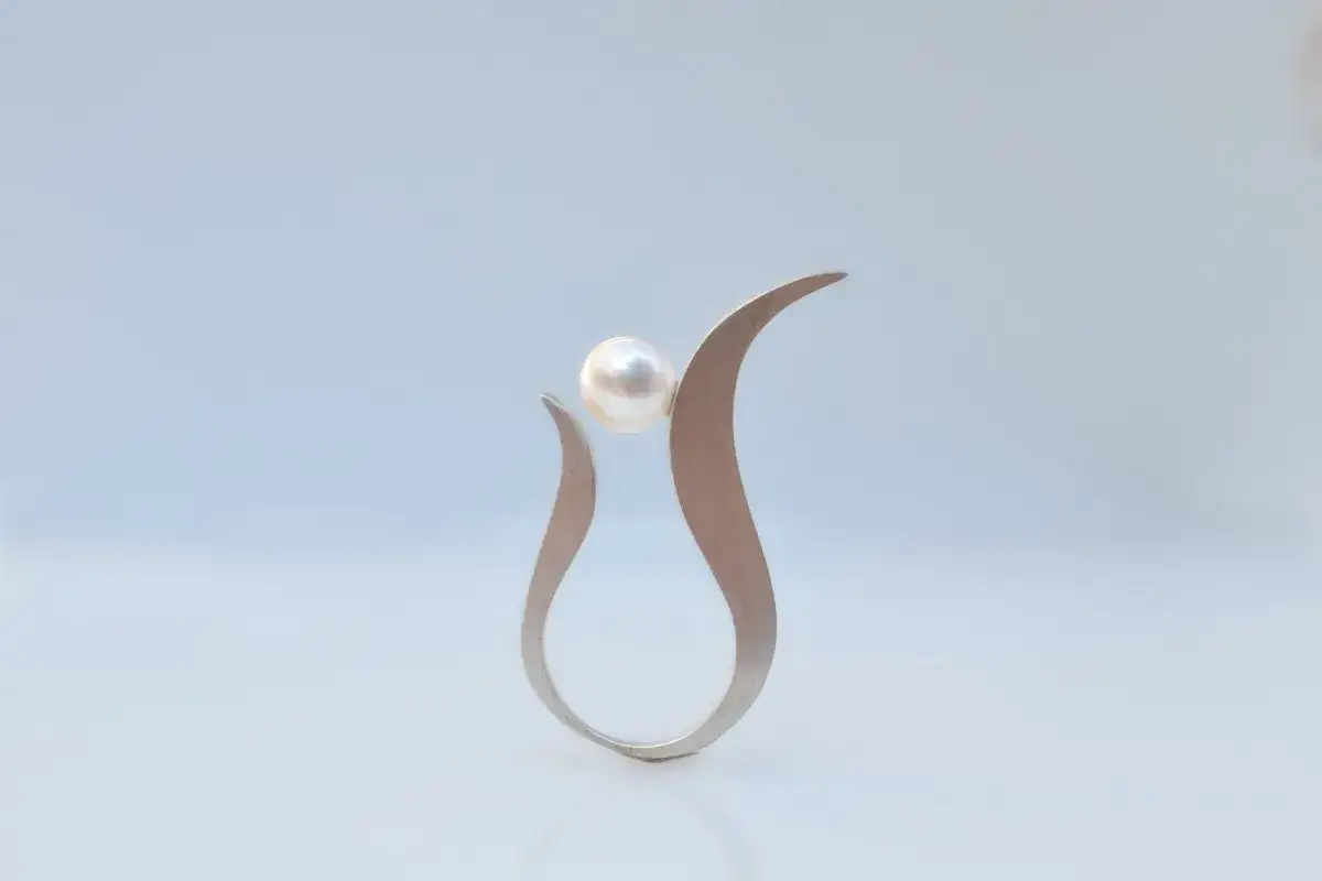 A modern silver ring cradles a luminous pearl, symbolizing purity and elegance. The silver pearl meaning is often associated with wisdom and serenity.