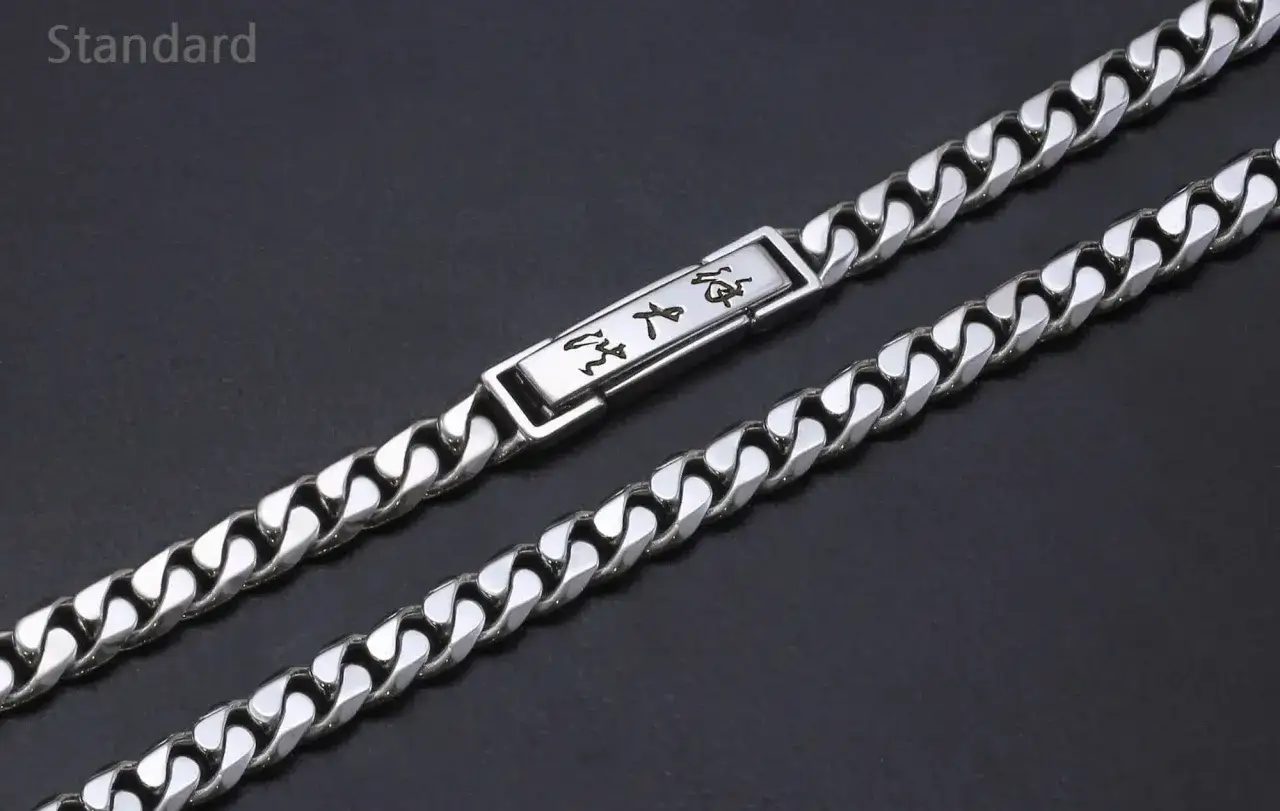 A man's platinum necklace with a rectangular tag featuring engraved Asian characters.
