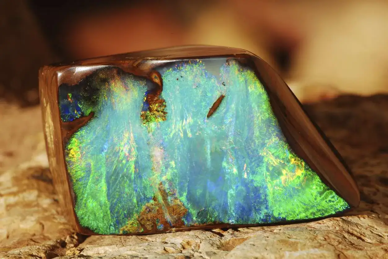A polished boulder opal with vibrant blue and green flashes, showcasing its opal spiritual meaning of hope and creativity.