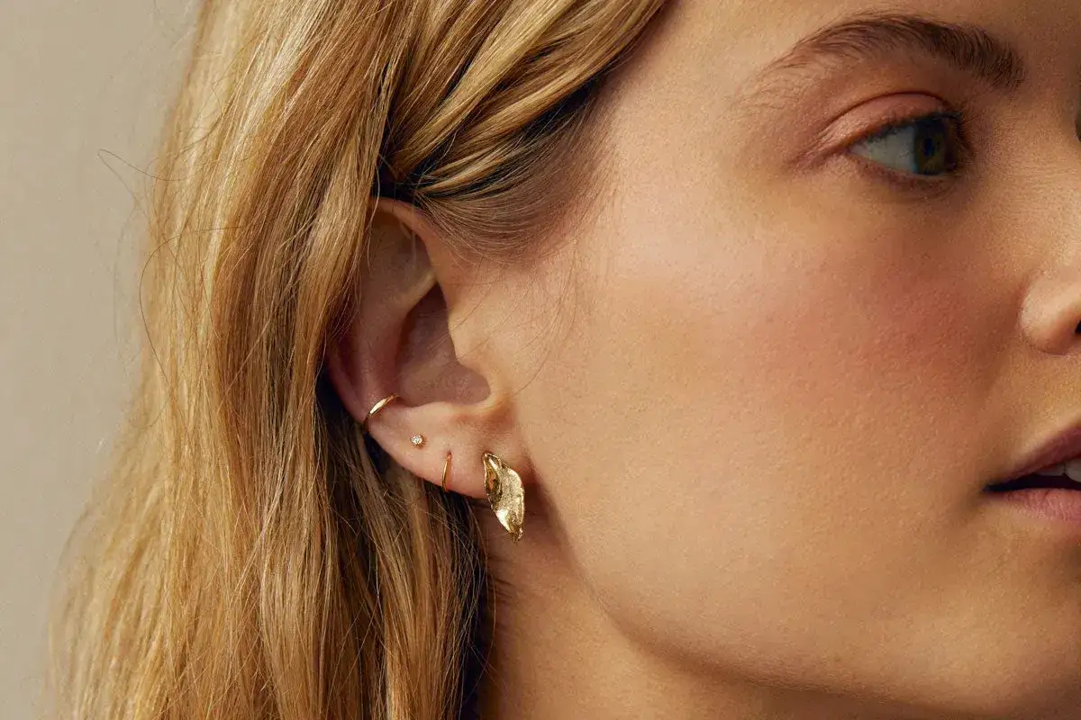Chic ear stack ideas featuring delicate gold hoops, a tiny diamond stud, and a unique leaf-shaped earring.