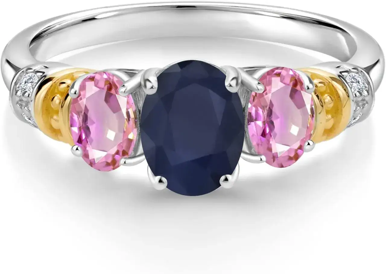 A stunning ring featuring a central oval sapphire, the sapphire september birthstone, flanked by pink oval stones and accented with gold and diamonds.