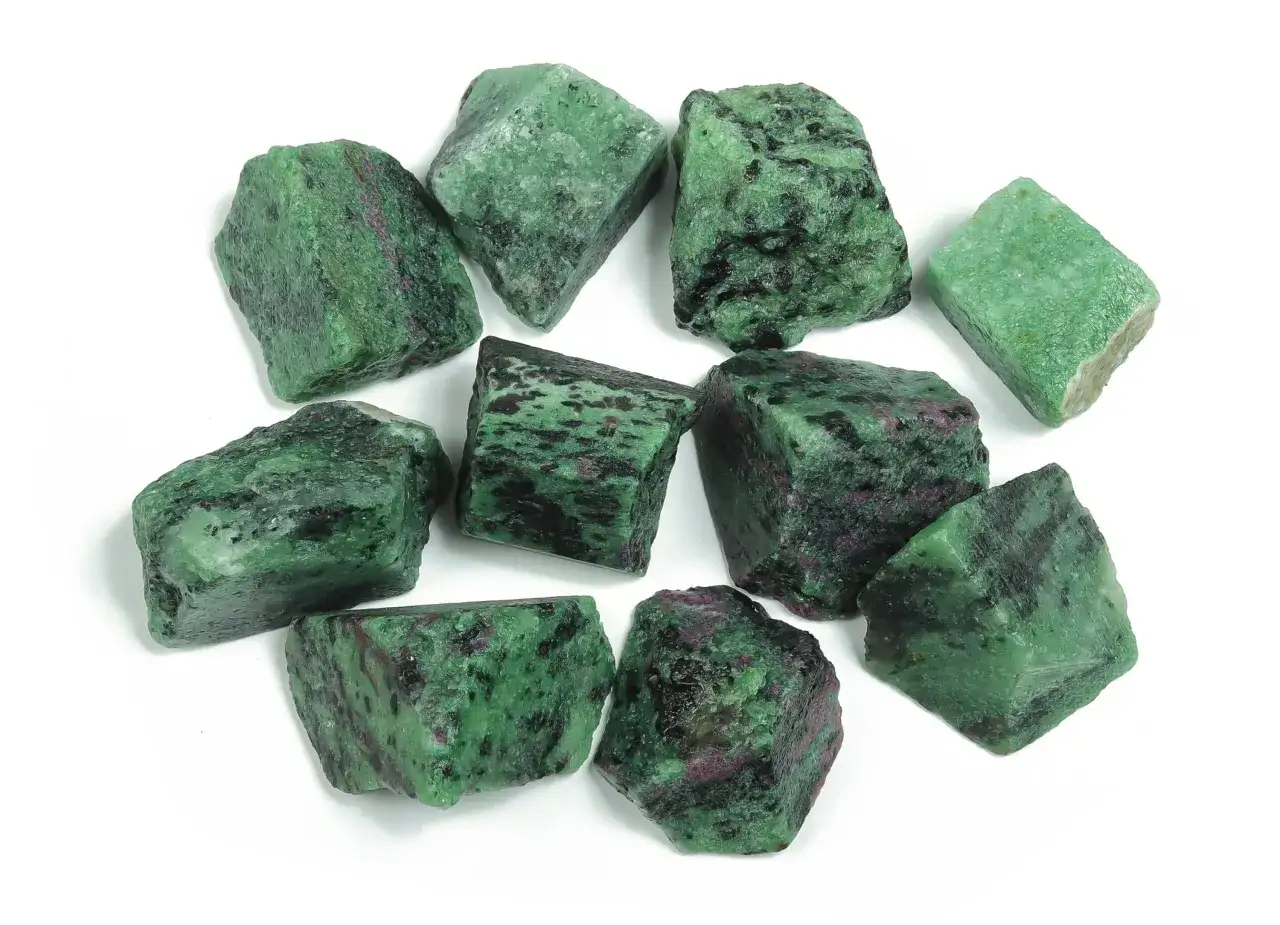 A collection of rough, uncut ruby in zoisite stones, showcasing their vibrant green and deep pink hues against a white background.