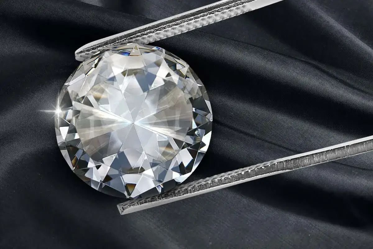 A large, brilliant diamond is held by silver tweezers against a dark, silky background. The facets of the diamond sparkle, showcasing the beauty of its diamond cut meaning.