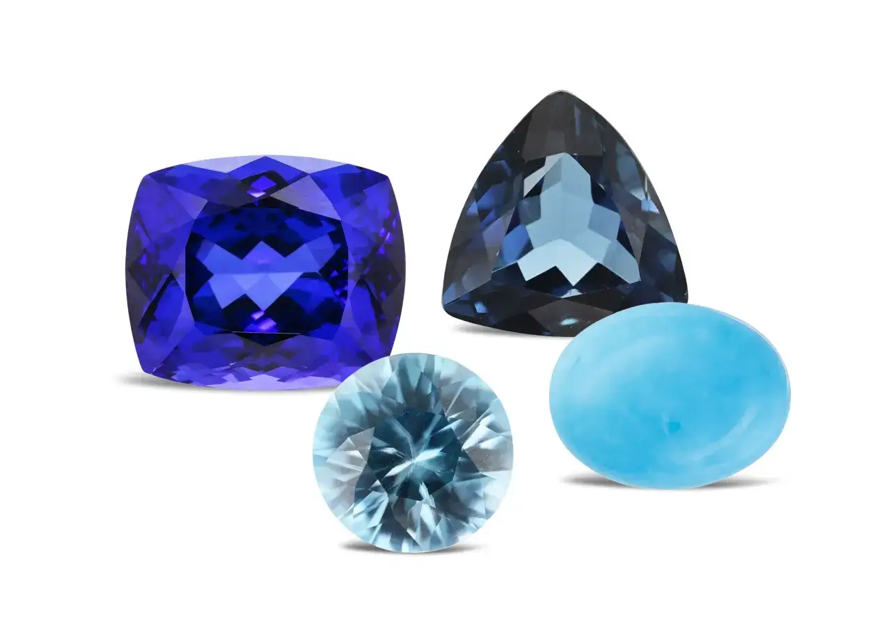 A cushion-cut tanzanite, a trillion-cut blue topaz, and a cabochon-cut turquoise are shown, representing what are December birthstones.