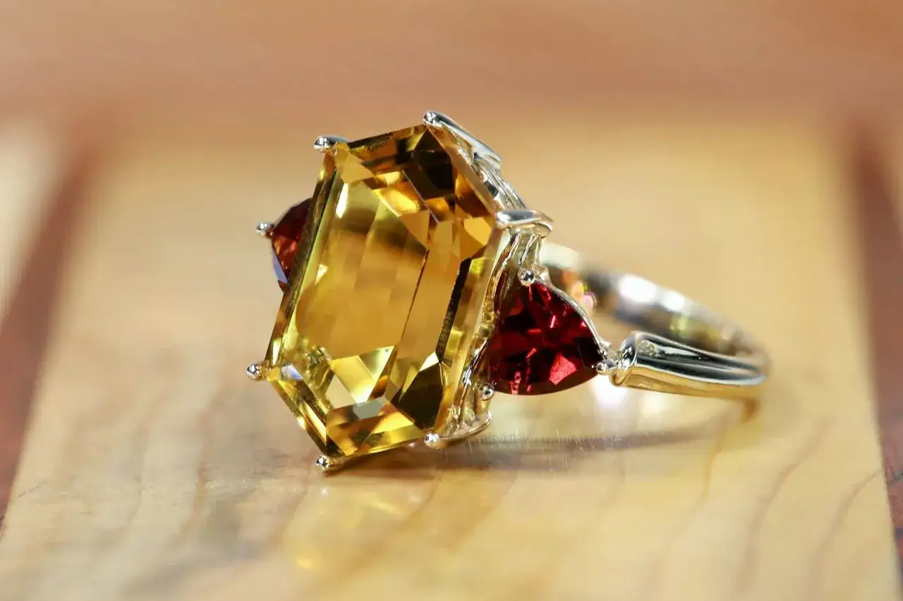 A stunning ring featuring a large emerald-cut yellow sapphire, flanked by triangular red stones. This piece embodies the radiant yellow sapphire benefits of joy and prosperity.