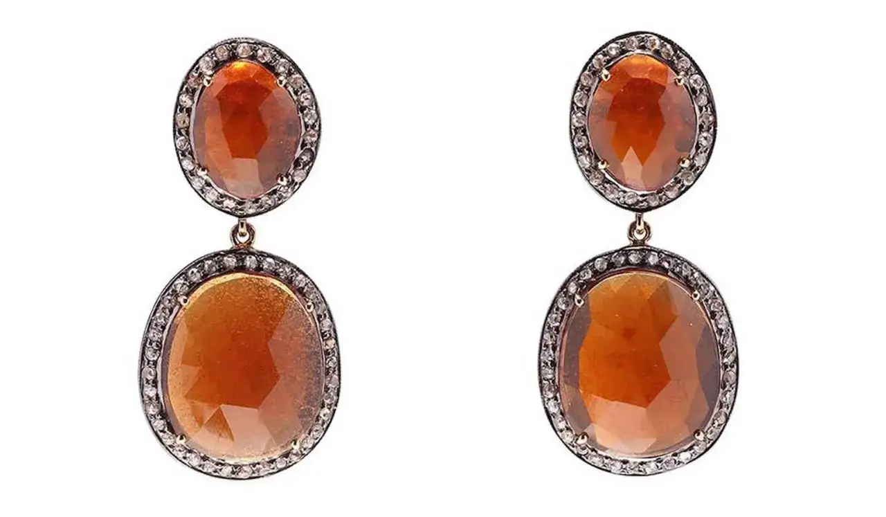 Dangle earrings featuring oval hessonite garnets, known for their hessonite garnet benefits, surrounded by small diamonds.