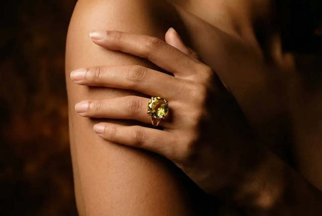 A hand wears a ring with a large, cushion-cut lemon quartz. This stone is often associated with the lemon quartz meaning of joy and abundance.