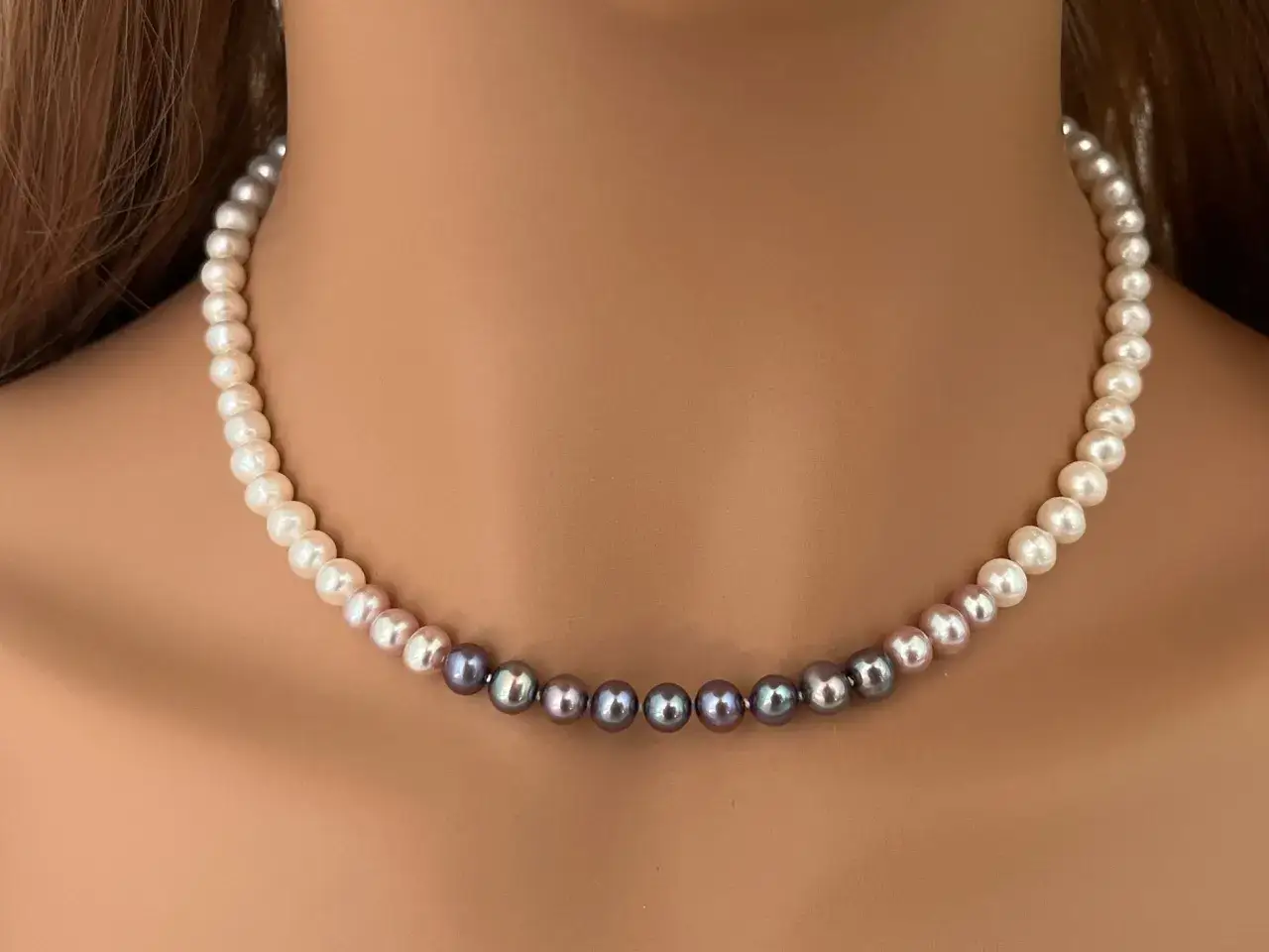 A pearl necklace transitions from white to grey, showcasing the timeless beauty of this natural jewel.